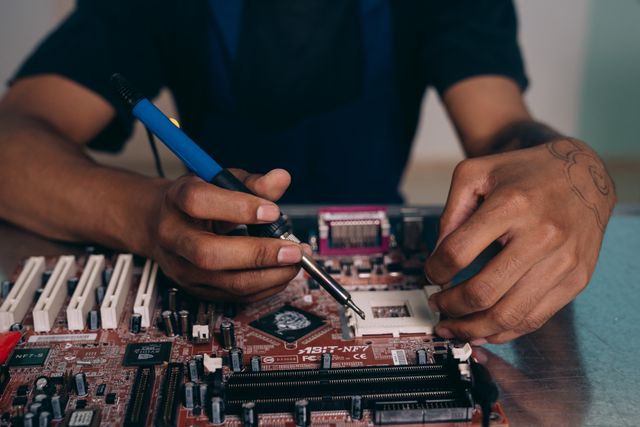 A technician carefully testing a desktop motherboard at the workbench