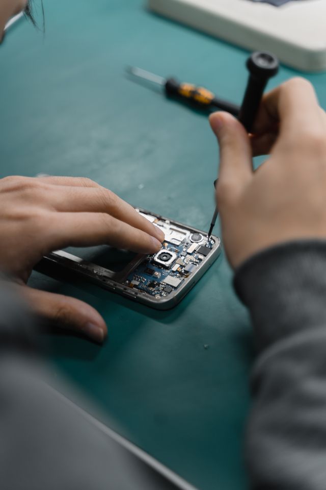 A technician opening a smartphone with a precision tool