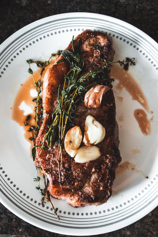 Seared steak with roasted garlic and rosemary on a porcelain plate