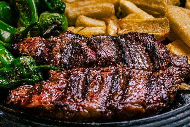 Sliced steak on a platter with grilled vegetables and potatoes