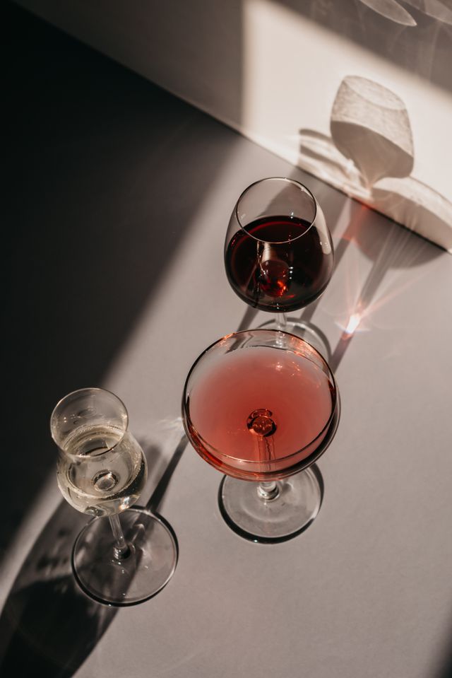 Glasses of red and rosé wine on an ivory tablecloth in afternoon light