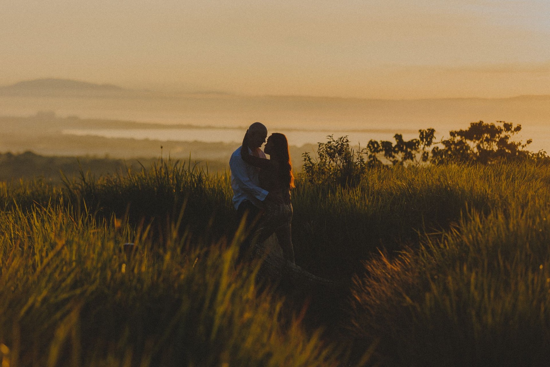 Couple embracing in a field at sunset