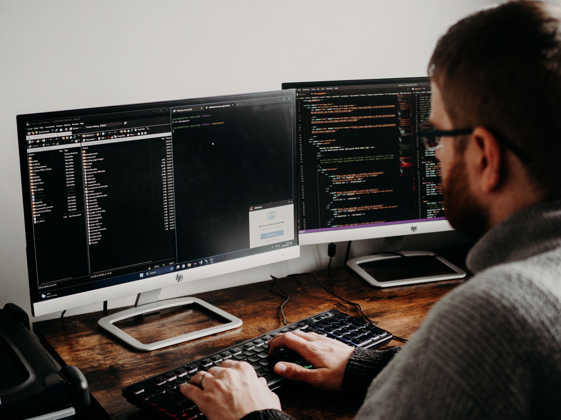 An engineer working across two desktop screens