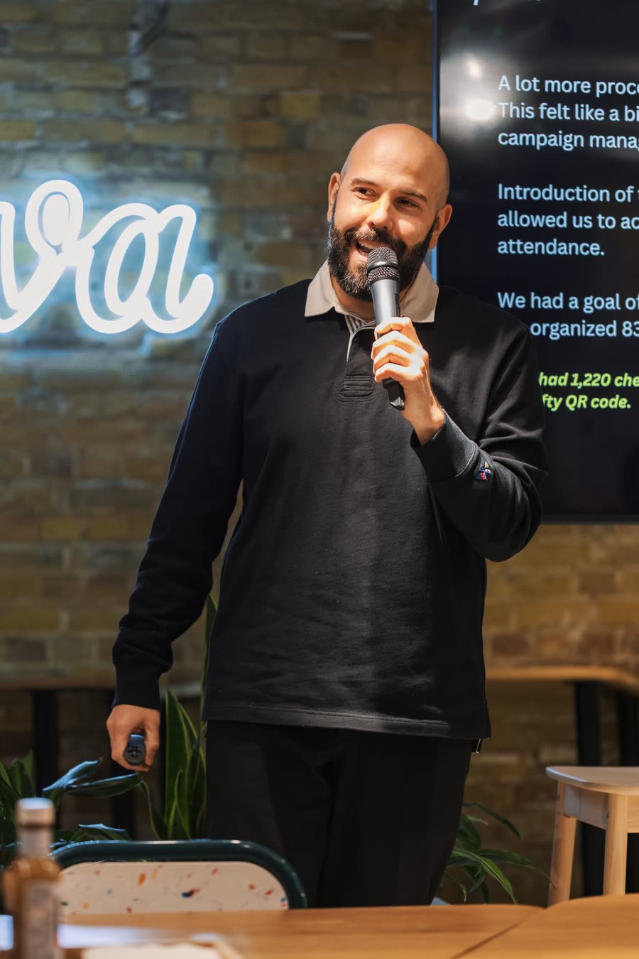 A speaker holding a microphone in front of presentation slides