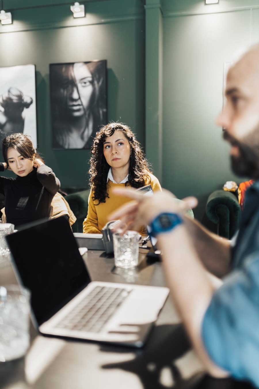People talking across a table with laptops and notes