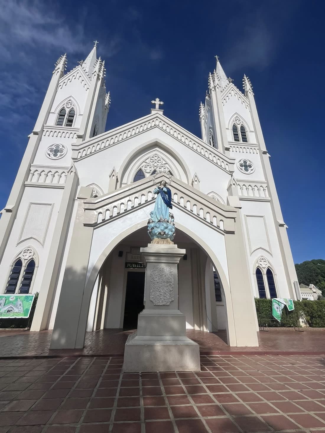The white Gothic facade of the cathedral with a statue of the Virgin in front