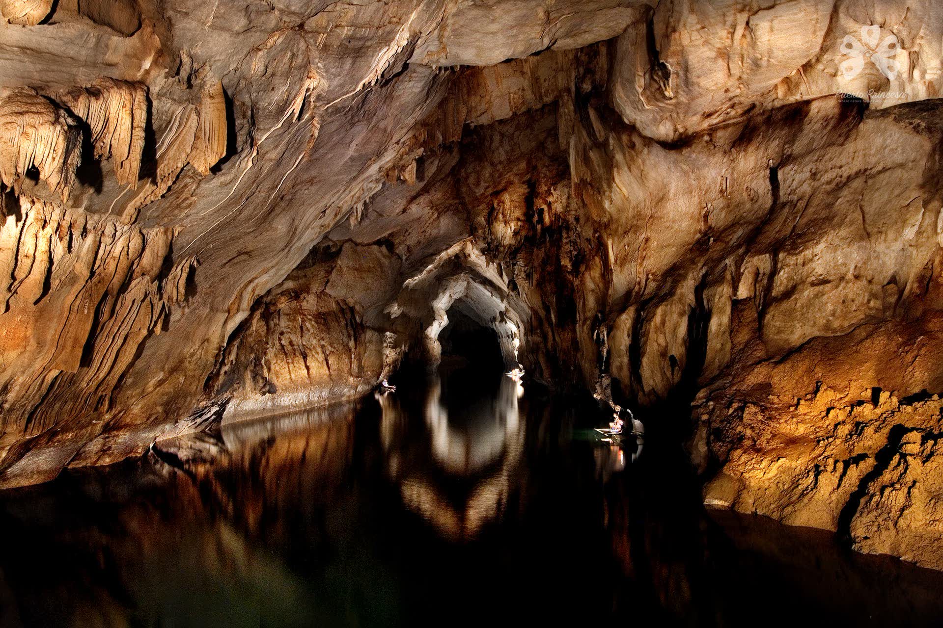 Lamplight on the ribbed limestone walls of a vast river cave