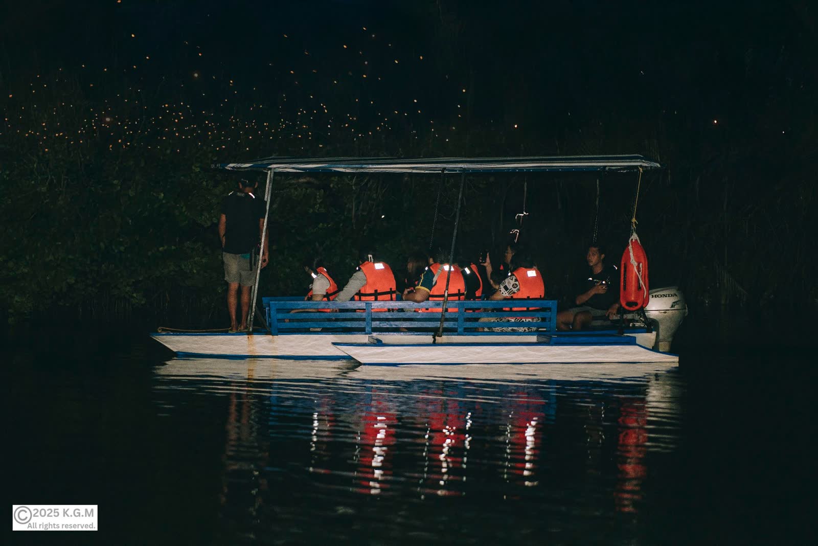 A boat of visitors in life vests gliding on a dark river at night