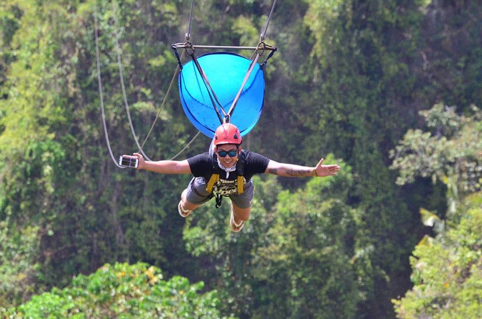 A rider on a zipline above the forest canopy