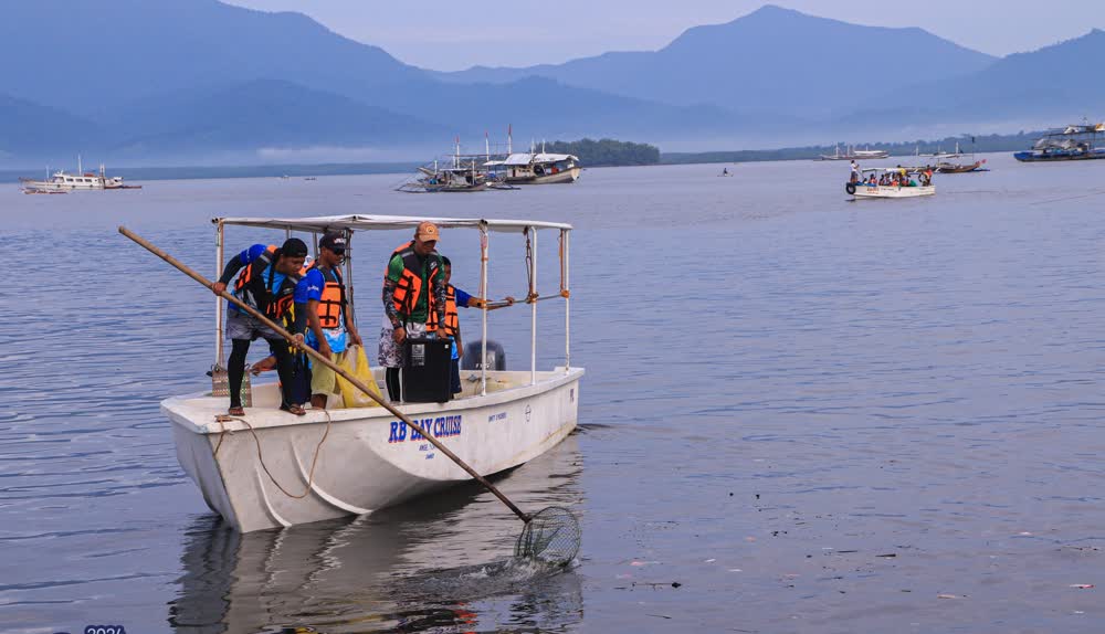 Volunteers in life vests on a small boat collecting litter from the bay