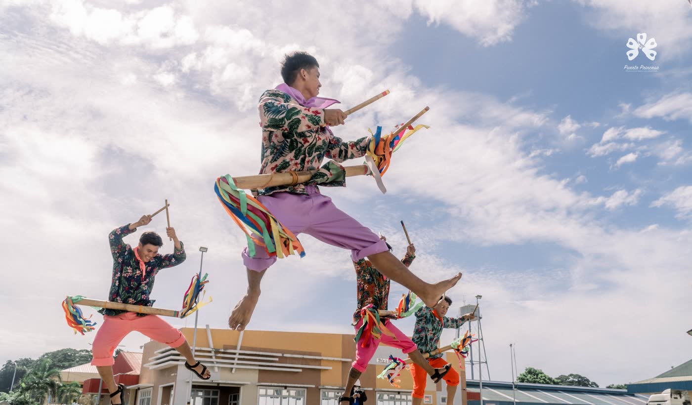 Street dancers in bright costumes leaping mid-air with props