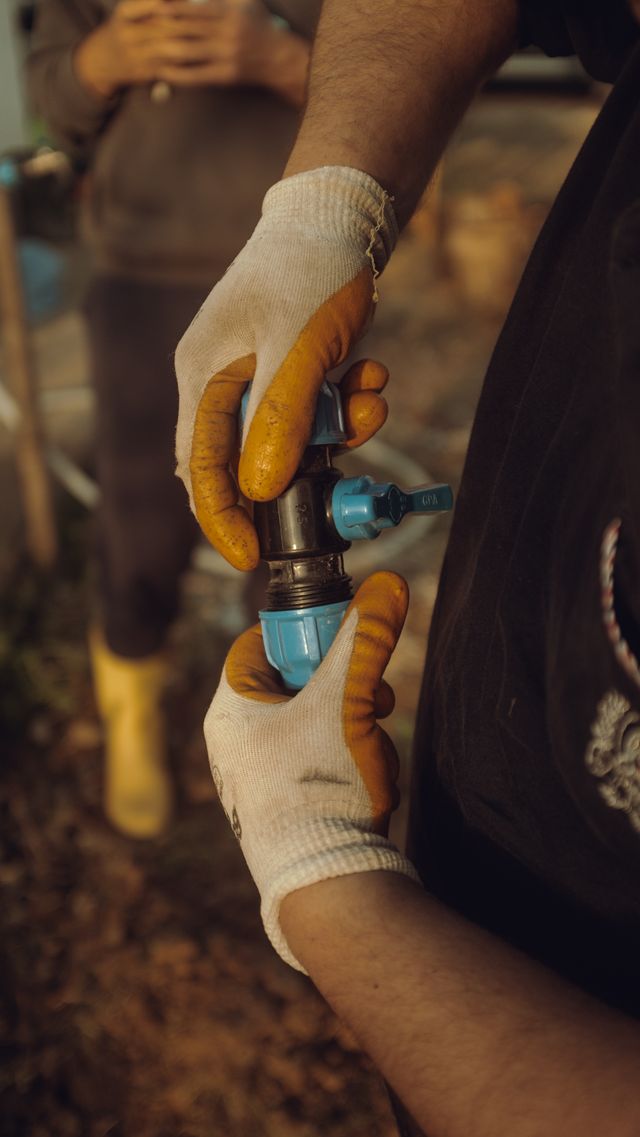 Gloved hands carefully connecting a pipe fitting