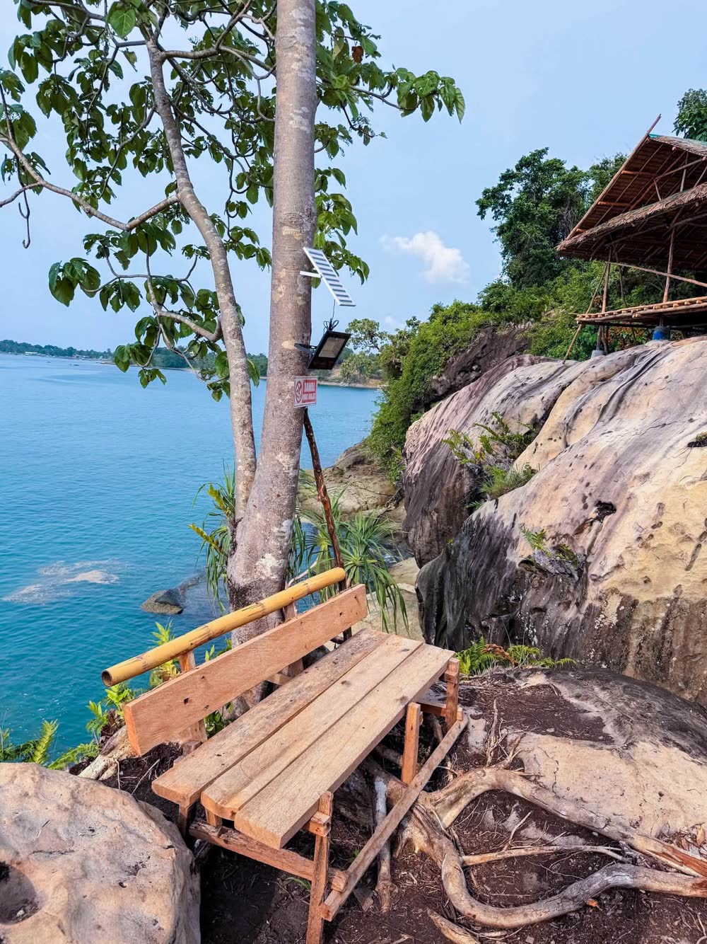 A wooden bench on a rocky ledge above turquoise water