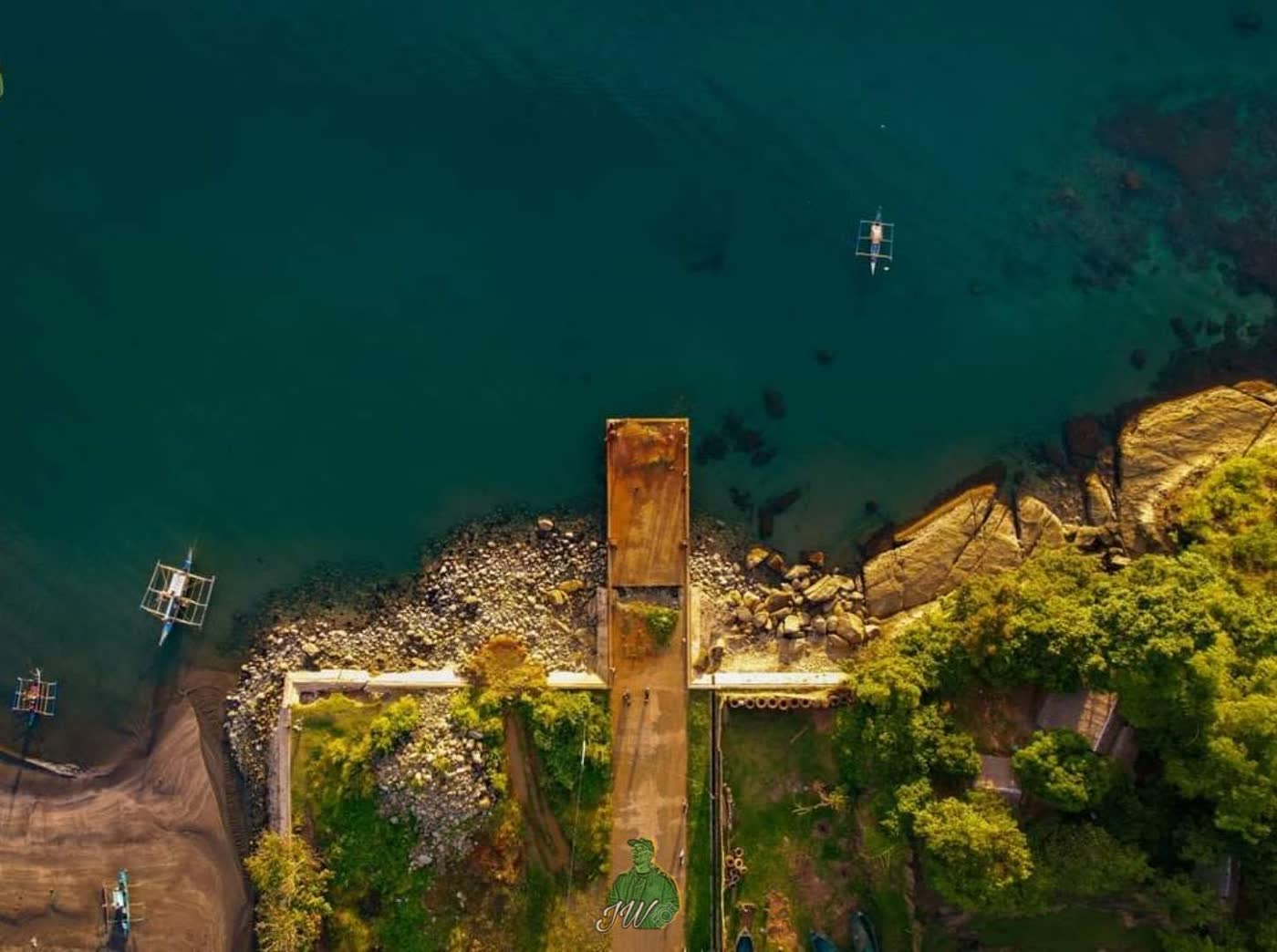 Aerial view of a jetty and rocky shore over deep green water