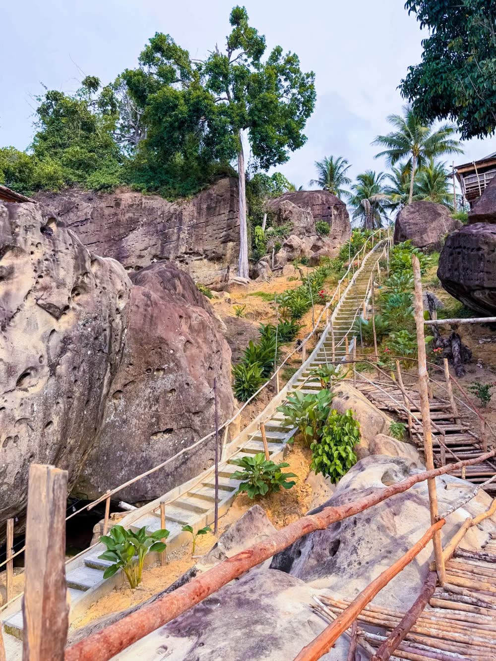 A wooden stairway climbing between huge boulders above the sea
