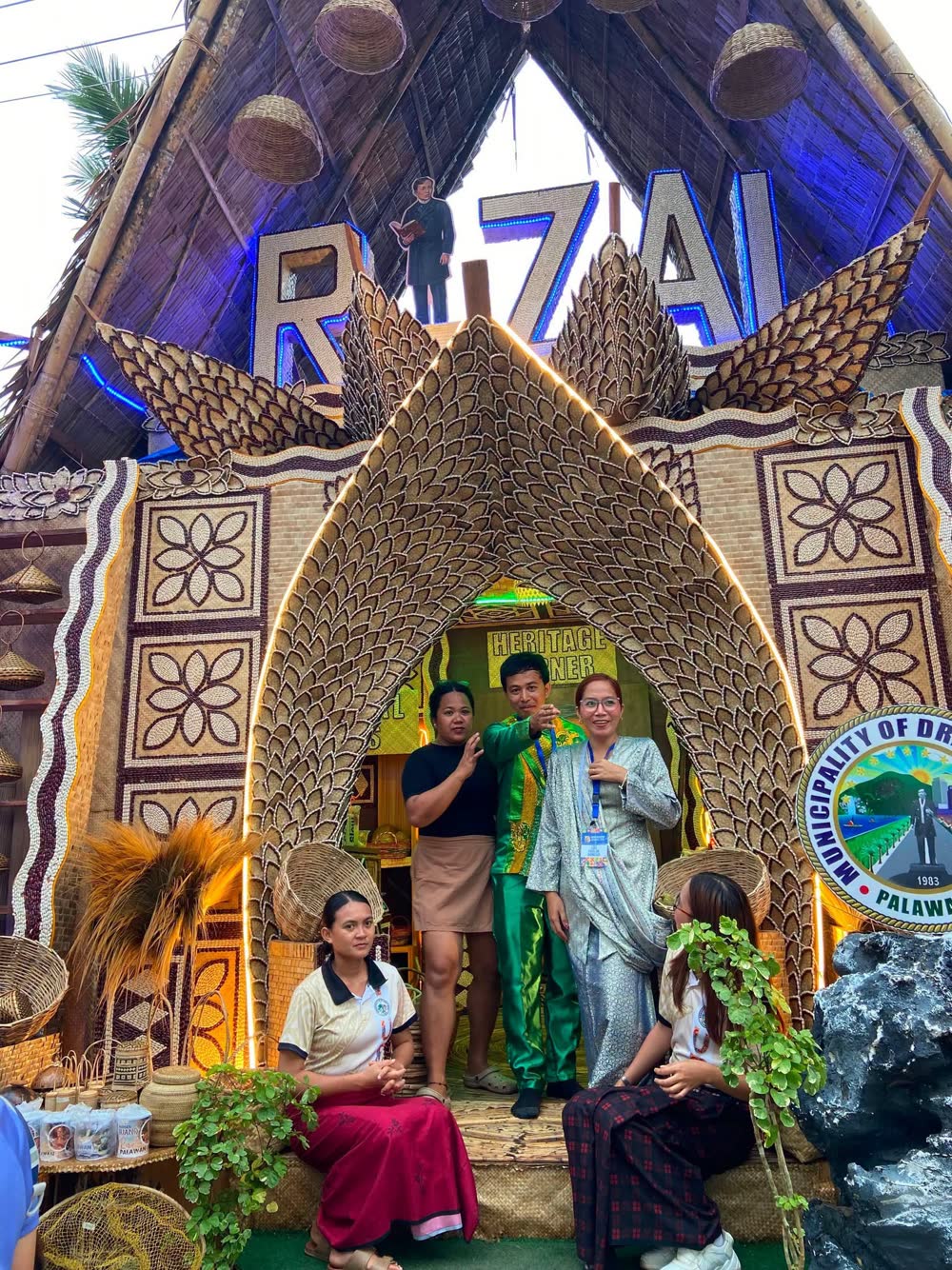 A grand woven archway spelling Rizal, with officials and dancers posing inside