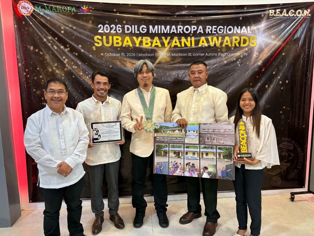 Officials holding a plaque and a display board in front of the 2026 DILG MIMAROPA Regional SubayBAYANI Awards backdrop