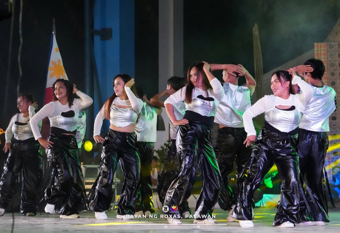 A dance troupe in black and silver performing on stage