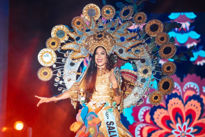 A pageant candidate in a gold costume with a sunburst headdress