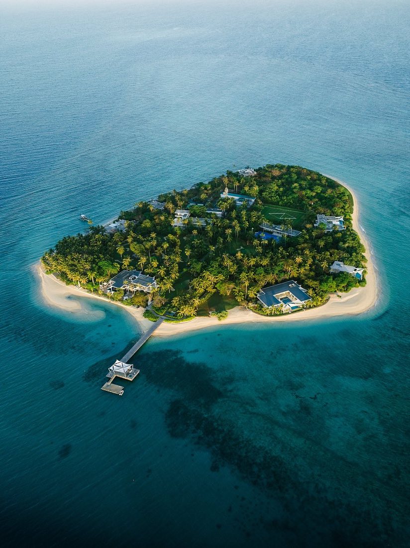 Aerial view of Banwa ringed by white sand and reef, with a long jetty