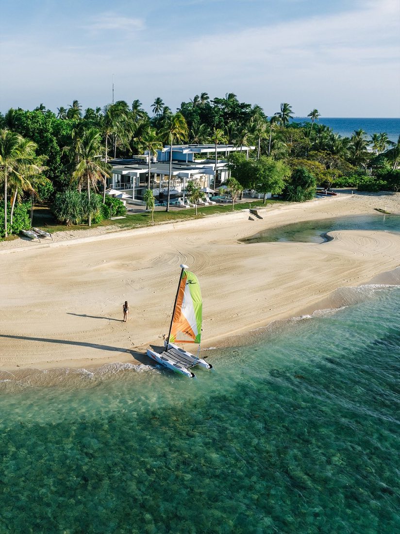 A catamaran with a yellow sail on the beach