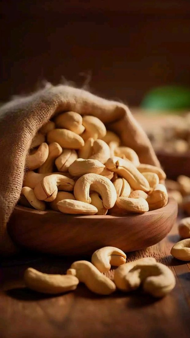 Cashew nuts spilling from a burlap sack into a wooden bowl