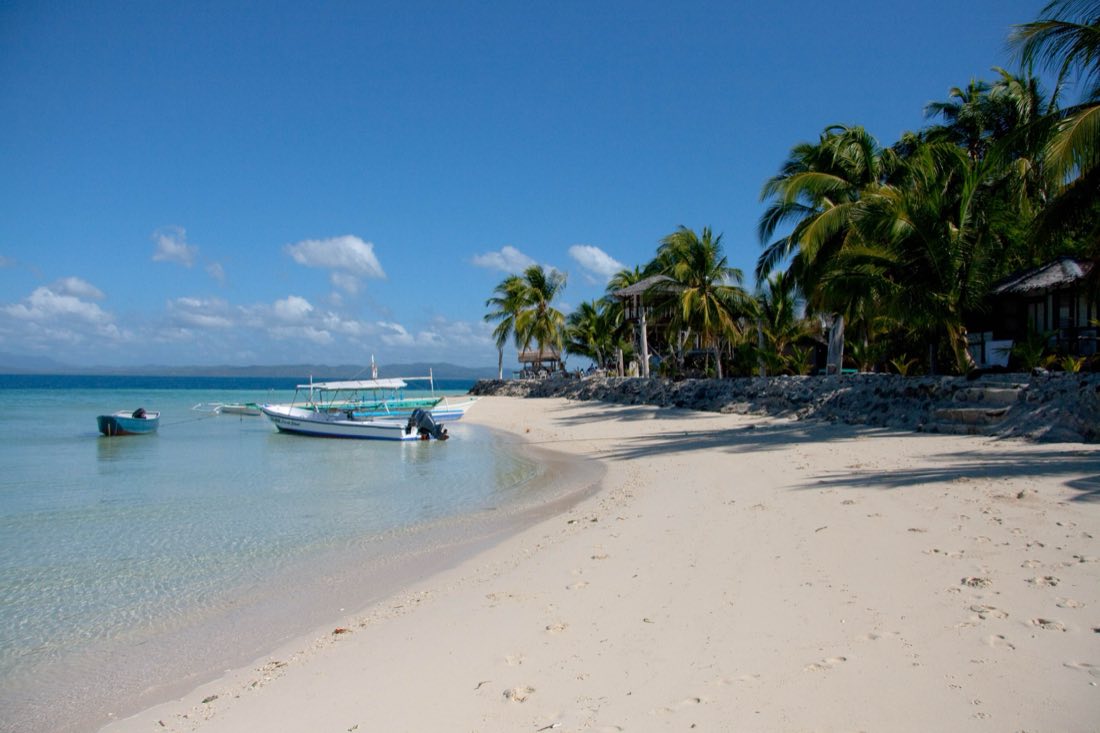 A white beach with palms and a bangka on Coco Loco Island