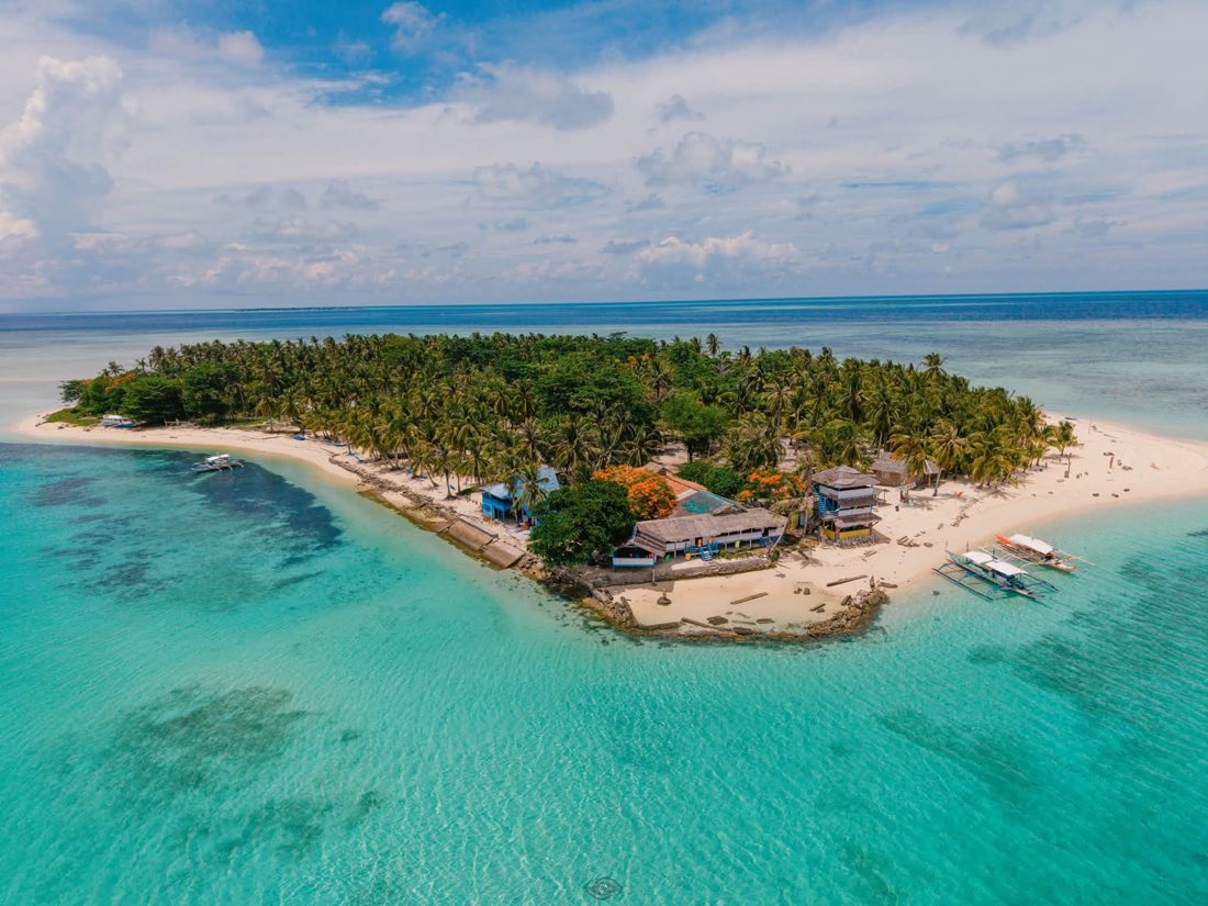 A small island with a white beach ringed by reef