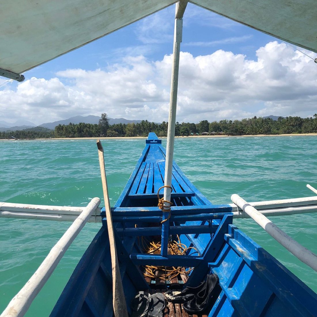 The bow of a blue bangka over turquoise water