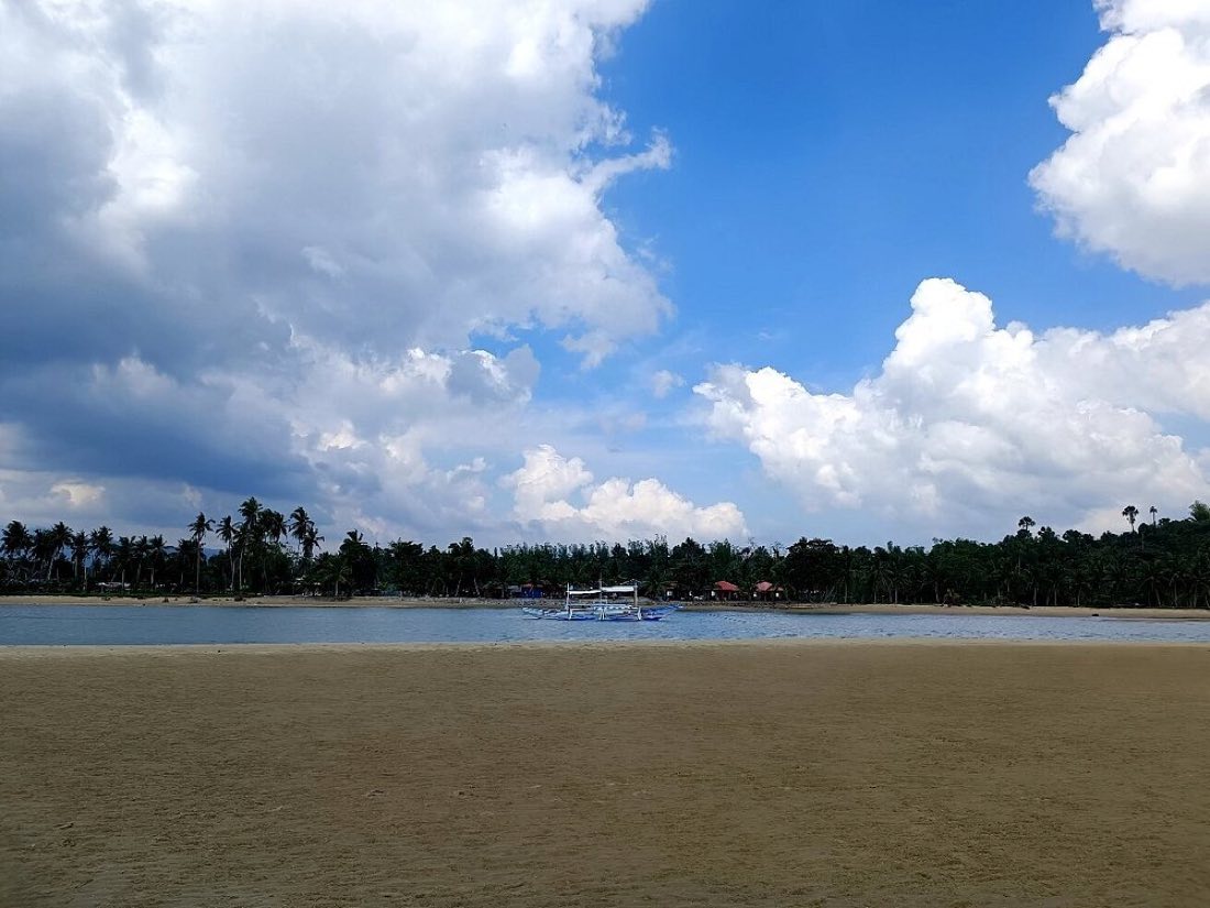 A wide sky with white clouds over a quiet beach