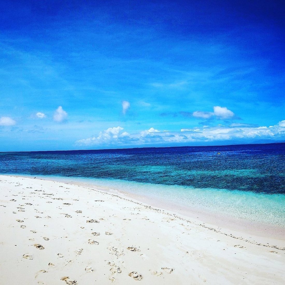 Clear blue water over the reef beside a white beach