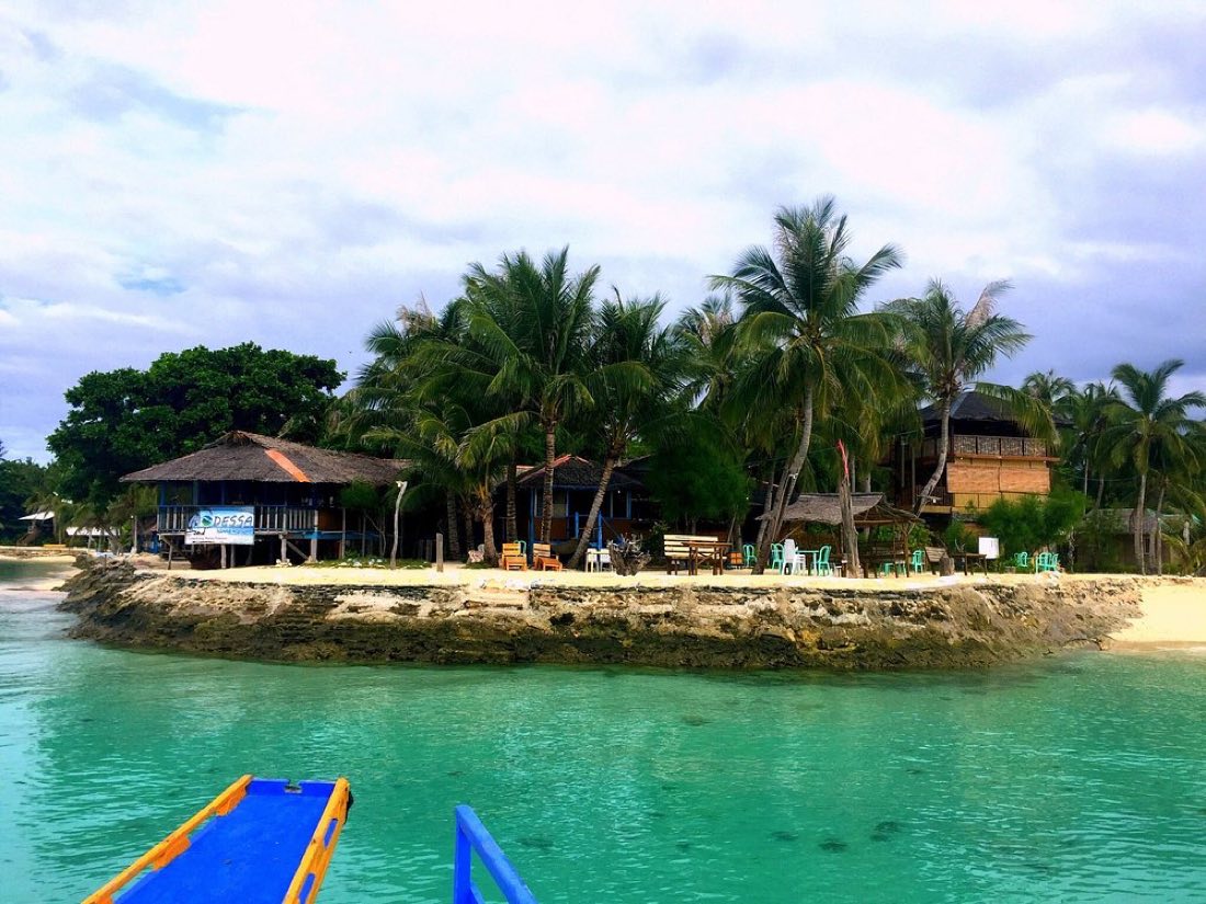Cottages among palms beside clear turquoise water