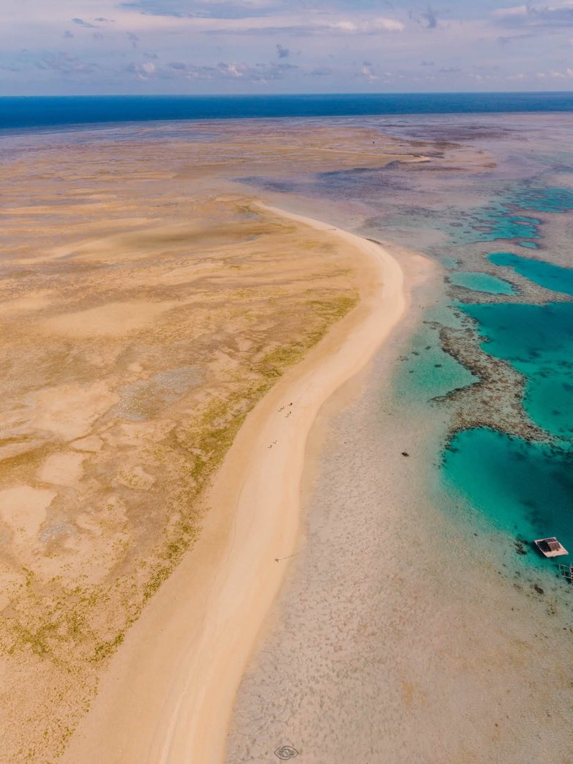 A curving white sandbar between deep and shallow water