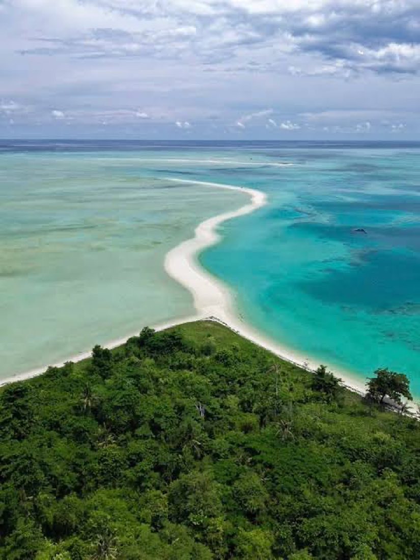 A hooked sandbar off a green island, seen from above