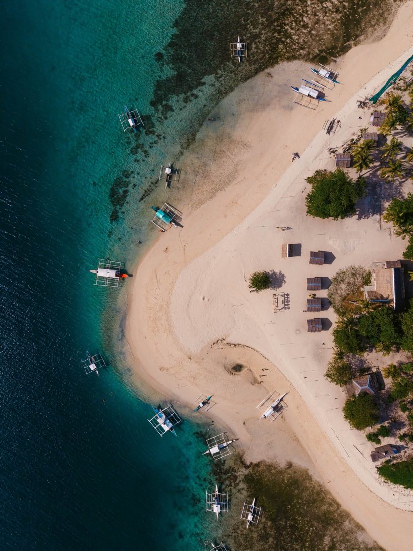 Bangkas pulled up along a white beach, seen from straight above