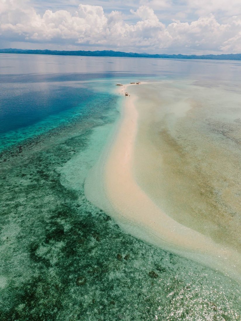 A white sand spit reaching into pale green shallows