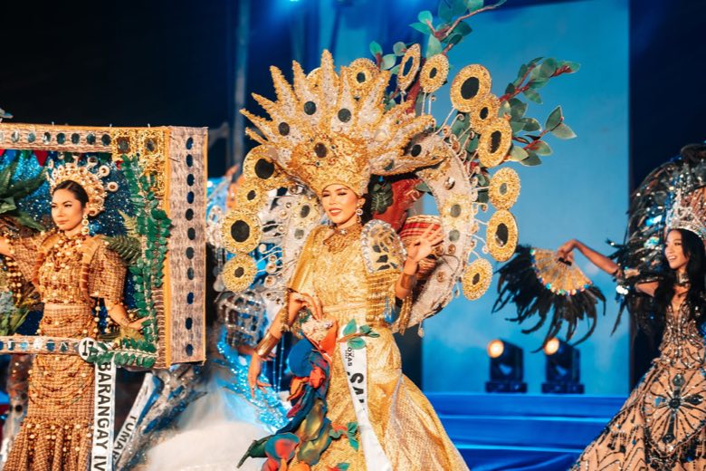 Pageant candidates in gold costumes on stage