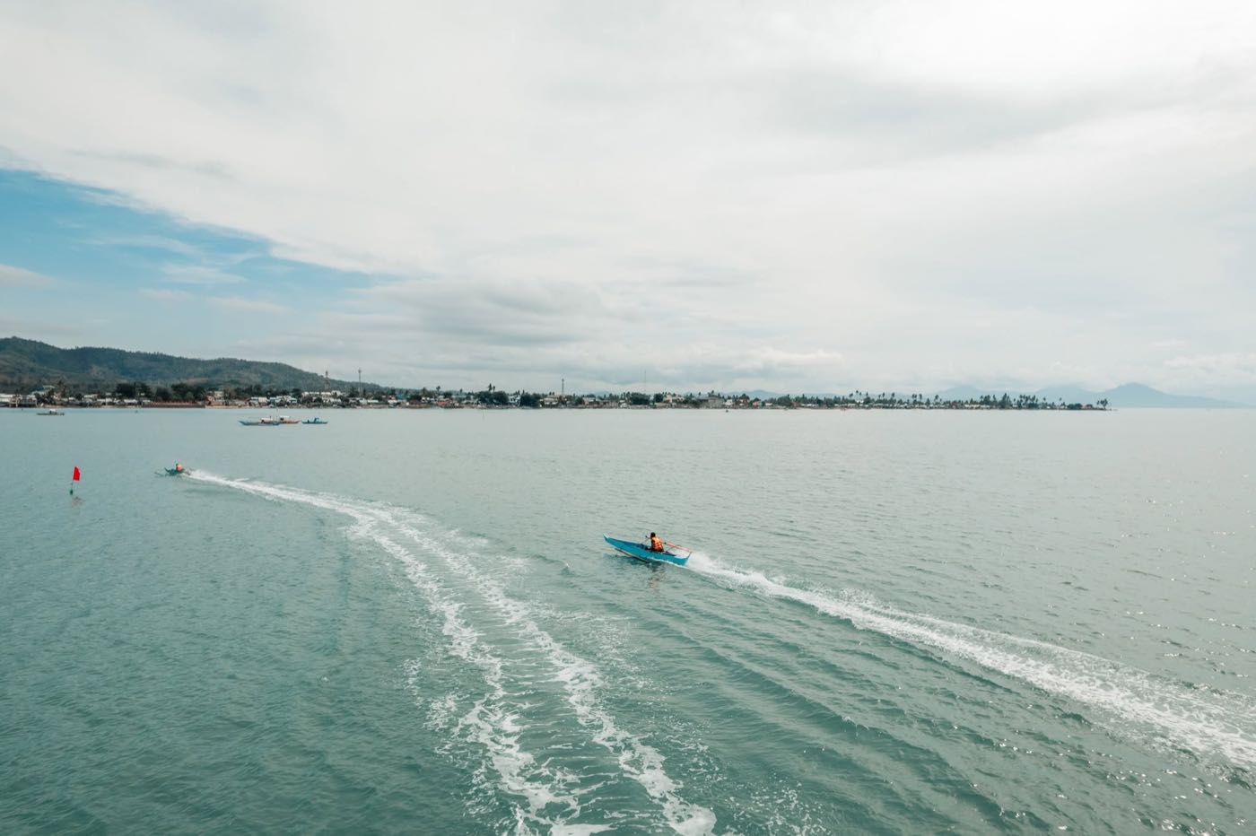 A boat cutting a white wake across the bay