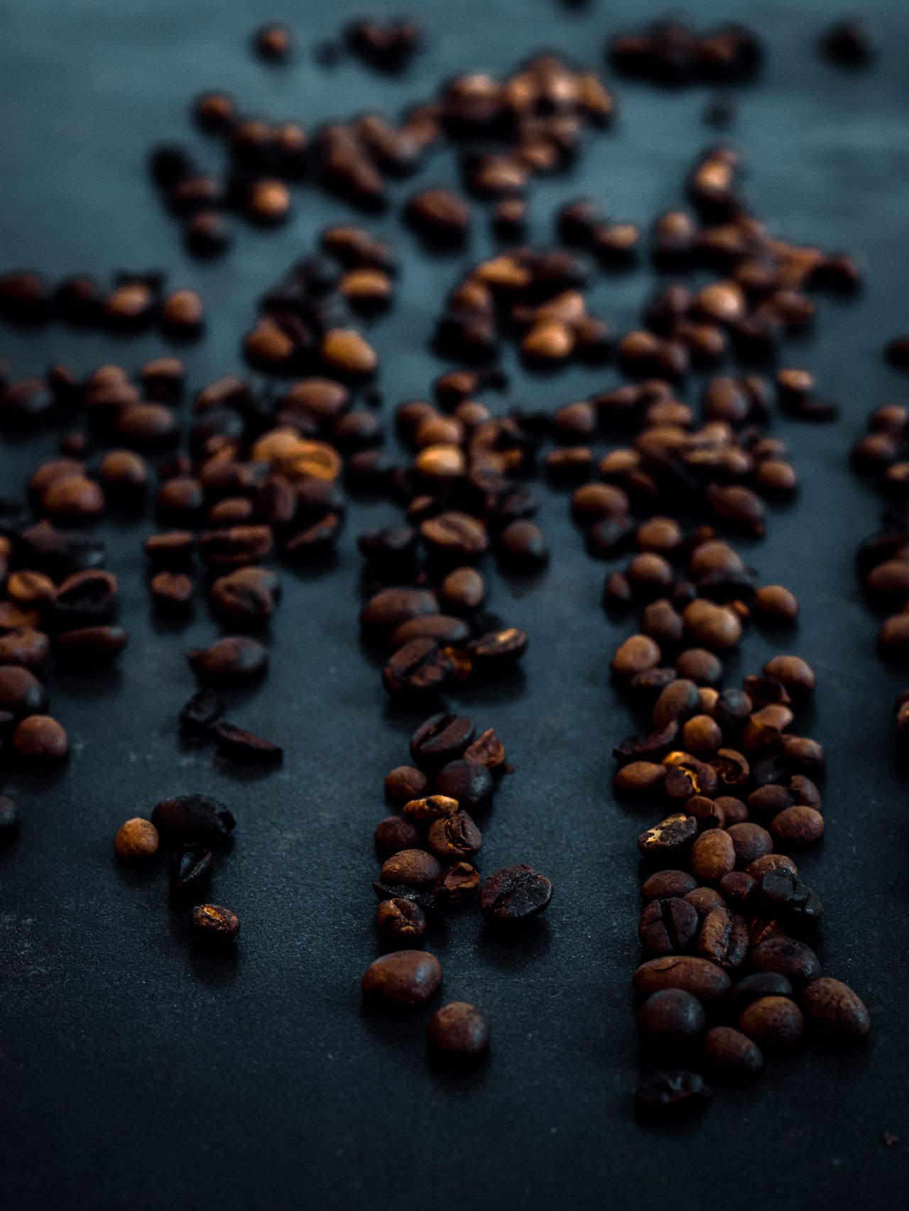 Roasted coffee beans scattered across a dark surface