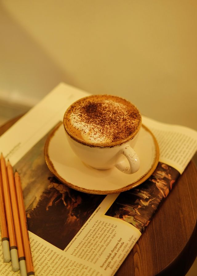 A warm cup of coffee beside an open book